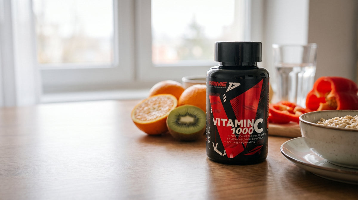 Flacon Vitamina C 1000 Prime lângă portocale, kiwi, ardei roșu și un castron cu fulgi de ovăz, pe o masă de mic dejun
